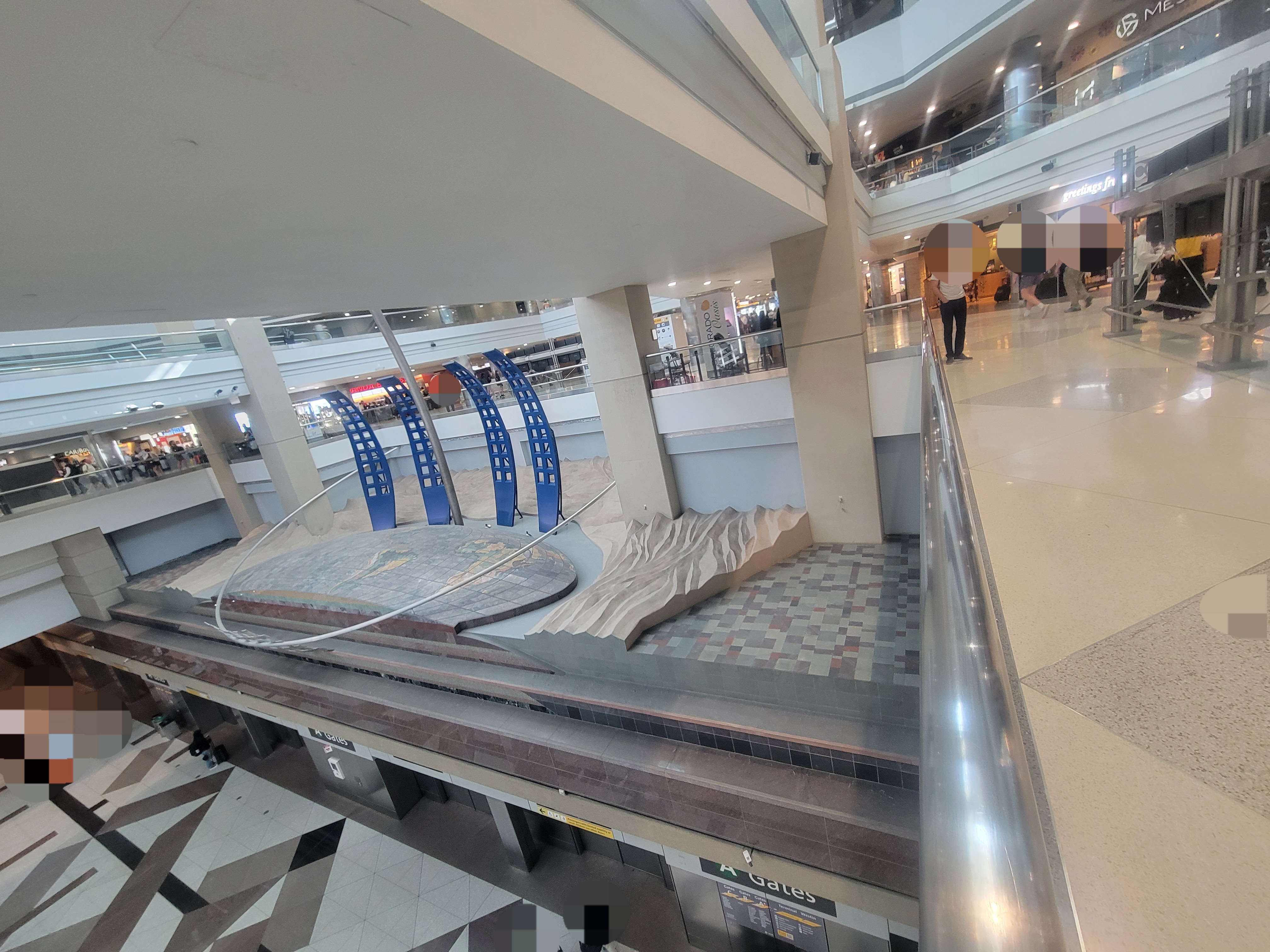 Art piece called Dual Meridian with this side showing concrete, earth, blue archs, and titanium arch surrounding it.